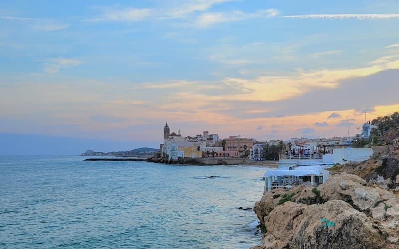 Skyline de Sitges al atardecer con la iglesia de Sant Bartomeu i Santa Tecla sobre el mar